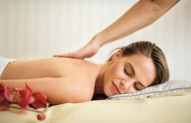 topless woman lying on bed getting massage