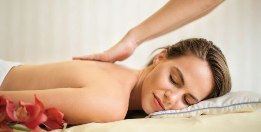 topless woman lying on bed getting massage